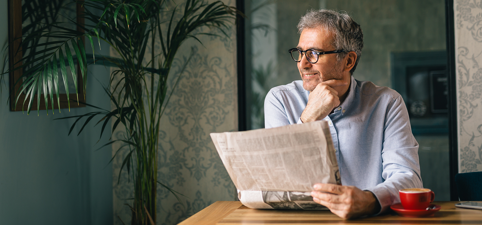 man reading the morning newspaper with coffee